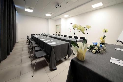 a large room with tables and chairs with flowers on them at Best Western Hotel Cristallo Mantova in Virgilio
