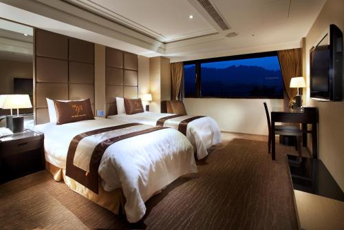 a hotel room with two beds and a desk and a window at Sun Moon Lake Hotel in Yuchi