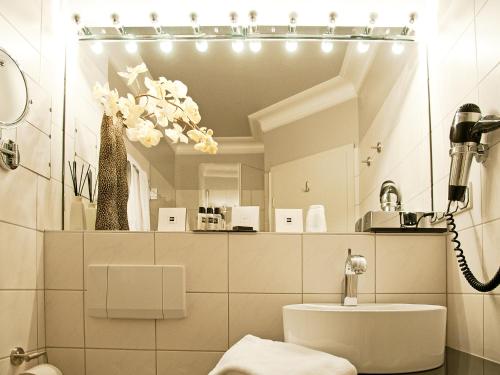 a white bathroom with a mirror and a sink at Amethyst Hotel Garni Lüneburg in Lüneburg