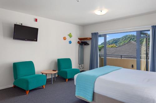 a bedroom with a bed and two chairs and a window at Awa Motel in Whakatane