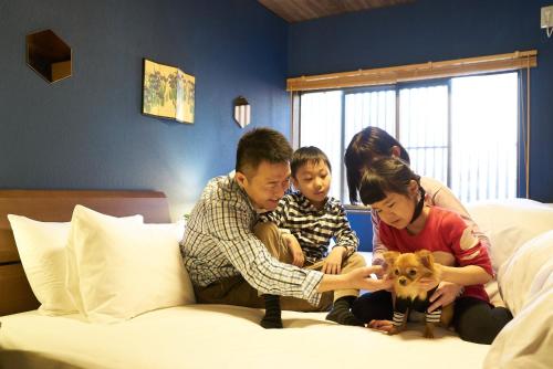 a family sitting on a bed with a dog at Nagomi 旅音 in Kanazawa