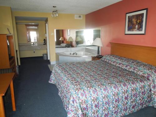 a hotel room with a bed and a bath tub at Kozy Inn Columbus in Columbus