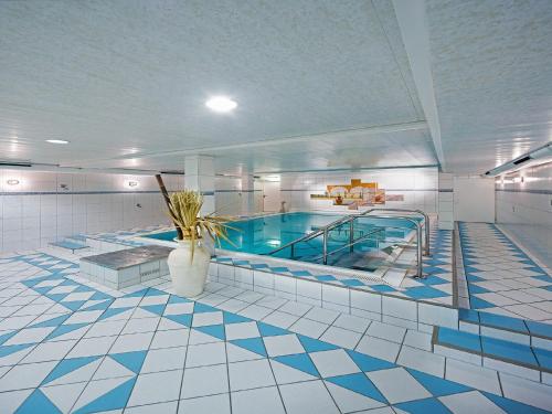 a large swimming pool in a large room with a tile floor at Art Hotel Aachen in Aachen