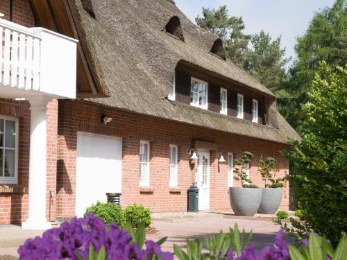 a brick house with a thatched roof with purple flowers at Amethyst Hotel Garni Lüneburg in Lüneburg