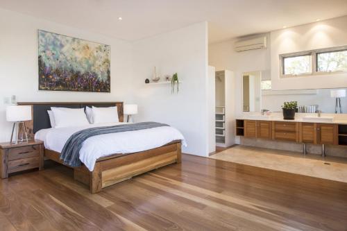 a bedroom with a bed and a bathroom with a sink at Cinque in Dunsborough