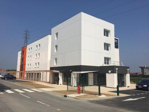 a white building on a street with a red fire hydrant at Ace Hôtel Paris Sud Villabe in Villabé