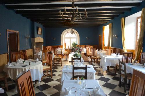 une salle à manger avec des tables et des chaises blanches dans l'établissement le Saint-Etienne, à Aubazines