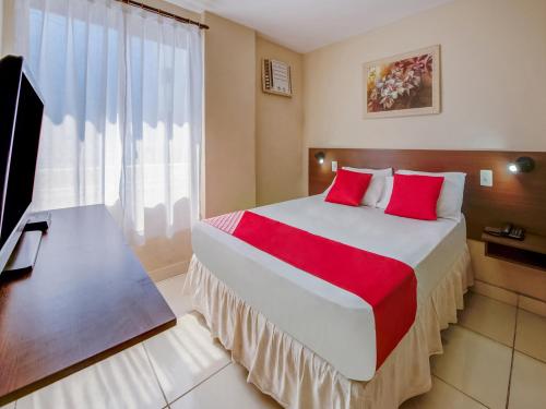 a bedroom with a large bed with red pillows and a television at OYO Rio Colinas Hotel, Rio de Janeiro in Rio de Janeiro