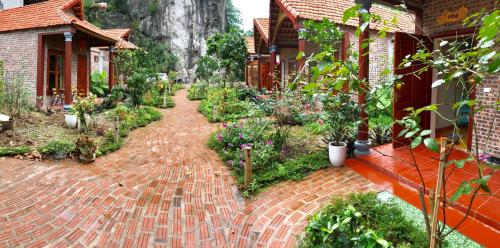 a brick walkway in a garden with flowers and plants at Ruby Homestay in Ninh Binh