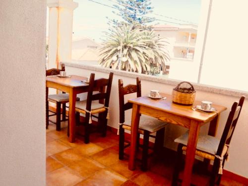 two tables and chairs in a restaurant with a window at Arena Bianca in La Caletta