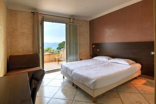 una camera con un grande letto e un balcone di Hôtel restaurant le Ressac a Campomoro