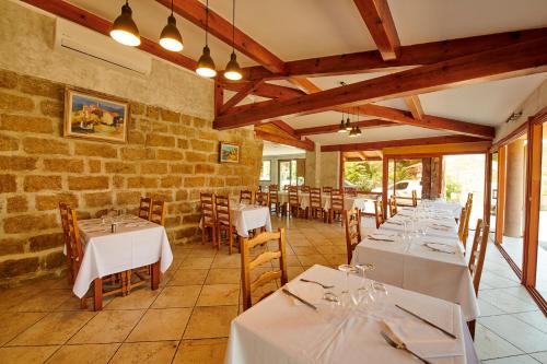 una sala da pranzo con tavoli e sedie bianchi di Hôtel restaurant le Ressac a Campomoro