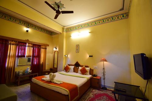 a hotel room with a bed and a television at Bani Park Hotel in Jaipur