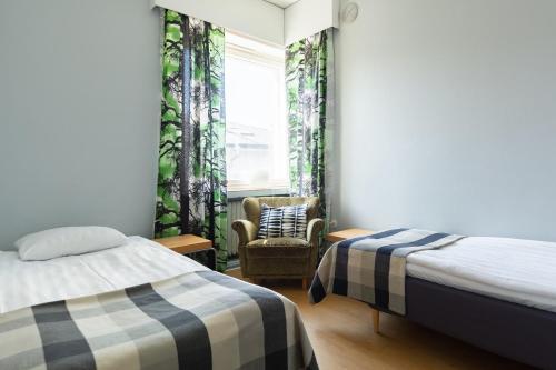 une chambre avec deux lits et une chaise et une fenêtre dans l'établissement Hostel Buisto, à Pori