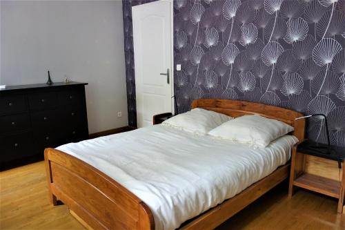 a bedroom with a wooden bed with a purple wall at LA MAISON DE ROSE in Limeray