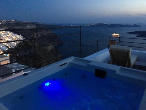 a hot tub on a balcony with a view of the ocean at Amelot Art Suites in Fira