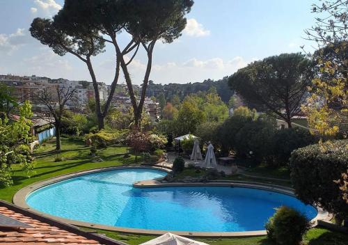 une grande piscine bleue dans une cour arborée dans l'établissement Villa Albina, à Rome