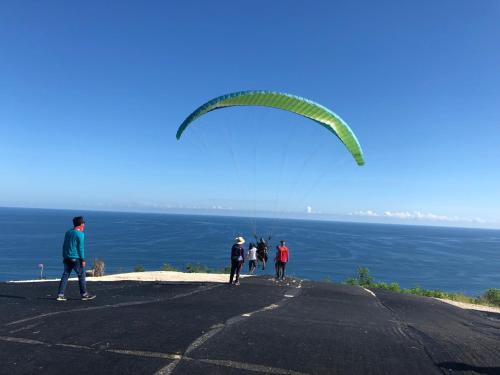 a group of people flying a kite on top of a mountain at The Ulus Klumpu in Uluwatu