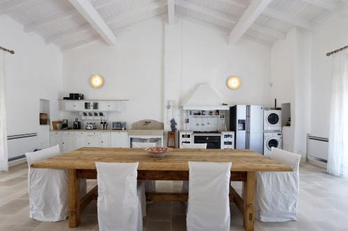 a large white kitchen with a wooden table and chairs at Masseria Fano Relais & Wine in Salve