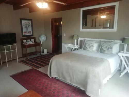 a bedroom with a large white bed and a mirror at Point Lodge Knysna in Knysna