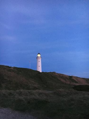 a white lighthouse sitting on top of a hill at Hirtshals Camping in Hirtshals