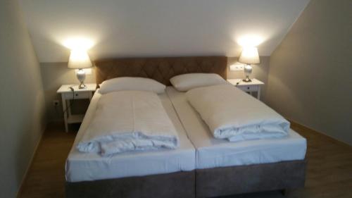 two beds in a small room with two lamps at Altstadtappartements Hartberg in Hartberg