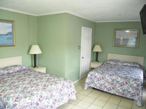 twee bedden in een slaapkamer met groene muren bij Bayfront Cottages in Rockport