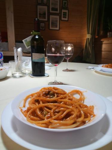 a plate of spaghetti on a table with a glass of wine at Rifugio Il Ginepro dell'Etna in Linguaglossa