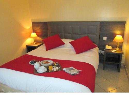 a hotel room with a bed with a tray of food on it at Hôtel Ariane in Istres