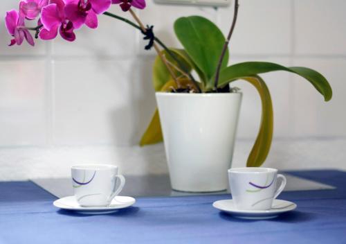 duas chávenas de chá e um vaso com flores sobre uma mesa em Ferienwohnung Gessert em Querfurt