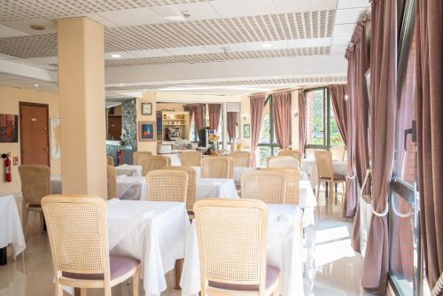 un comedor con mesas y sillas blancas en Hôtel Garabel en Plaisir