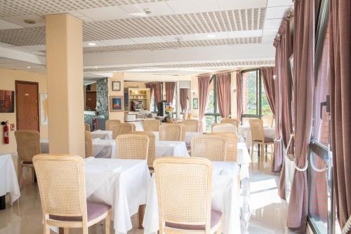 a dining room with white tables and chairs at Hôtel Garabel in Plaisir