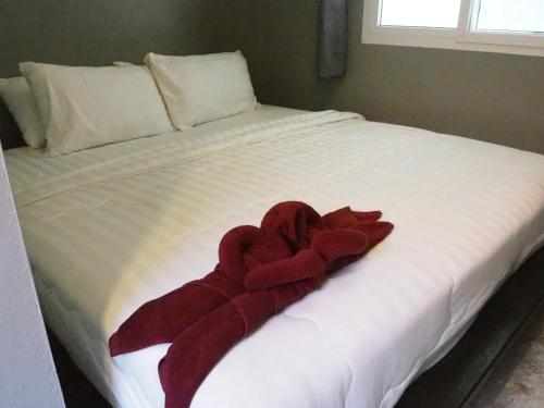 a red towel laying on a white bed at Lotto House in Ko Samed