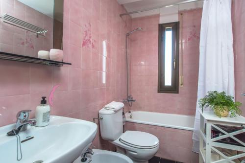 Baño de color rosa con aseo y lavamanos en Costabravaforrent Perris en L'Escala