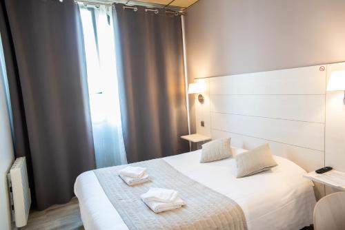 a bedroom with a white bed with two towels on it at Hôtel Garabel in Plaisir
