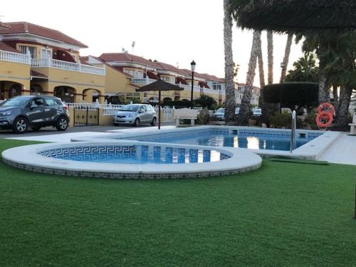 een zwembad in het midden van een tuin met auto's bij Macerana 1, Torreta III, Torrevieja in Torrevieja