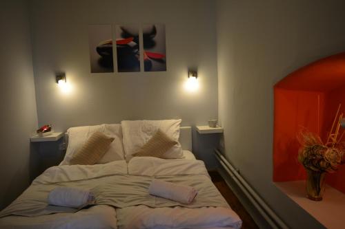 a bed in a room with two pictures on the wall at Főtér Apartmanház Szentendre in Szentendre