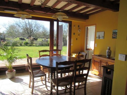 une salle à manger avec une table et des chaises et une fenêtre dans l'établissement La Hugotière, à Friville-Escarbotin