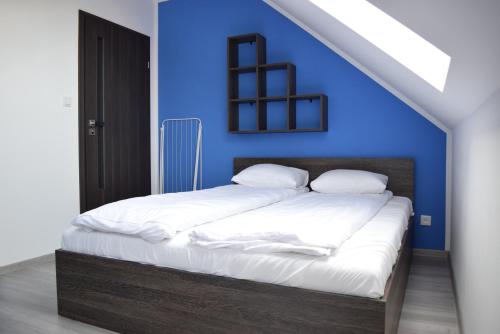 a bedroom with a bed with a blue wall at Willa Natenczas in Jarosławiec