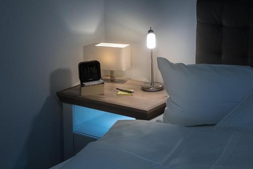 ein Bett mit einem Nachttisch mit einer Uhr und einer Lampe in der Unterkunft Premium Business Apartment in Oberkochen in Oberkochen