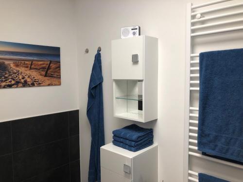 a bathroom with a white cabinet and blue towels at Prerow „Seaside“-strandnah! in Prerow