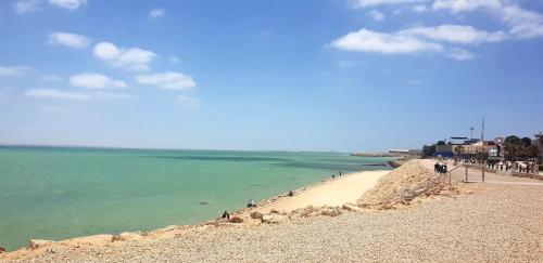 a beach with people sitting on the sand and the water at La Maison Jaune Dakhla Maison d'hôtes in Dakhla
