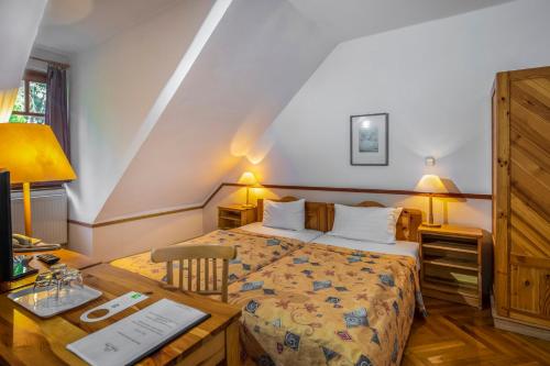a bedroom with a bed and a desk and a table with a computer at Bakony Hotel in Bakonybél