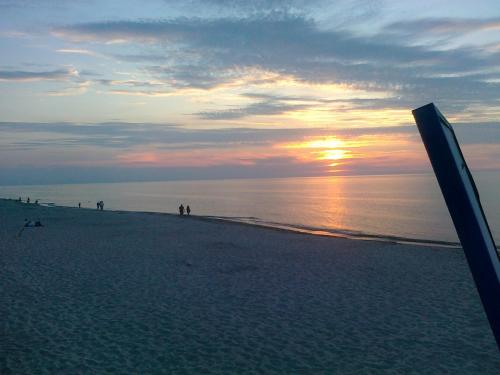 a beach with the sun setting on the horizon at Willa Sarbinowo in Sarbinowo