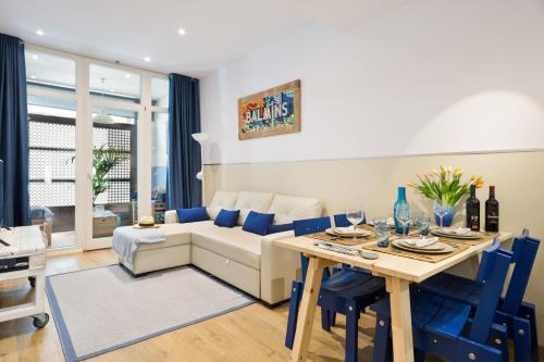 sala de estar con sofá y mesa con sillas azules en Sans Souci Quality Apartments, en Sitges