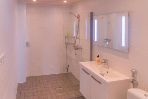 ein weißes Badezimmer mit einem Waschbecken und einem Spiegel in der Unterkunft Jääskän Loma Kojolapark, asunto 1, Alahärmä, Kauhava in Holma