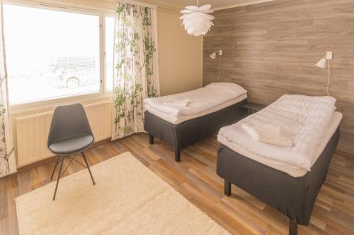 2 Betten in einem Zimmer mit einem Stuhl und einem Fenster in der Unterkunft Jääskän Loma Kojolapark, asunto 1, Alahärmä, Kauhava in Holma