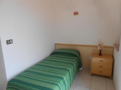 a small bedroom with a green bed and a nightstand at PENSIONE VERDE LUNA in Orbetello