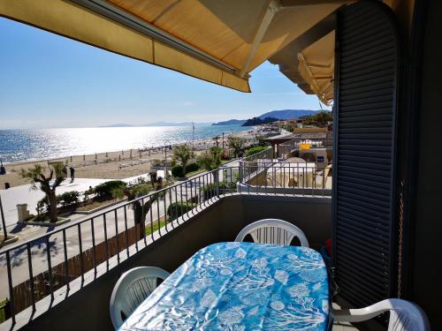 balcón con mesa y sillas y vistas a la playa en Appartamenti Lungomare Via Roma, en Castiglione della Pescaia