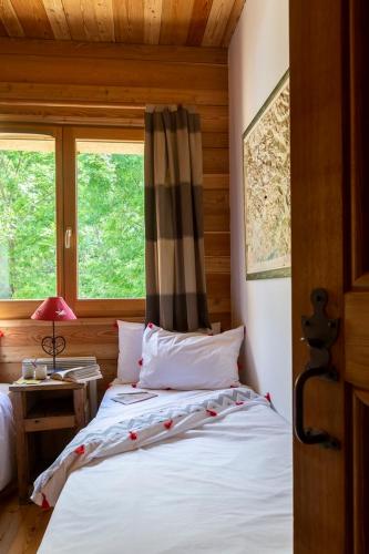 une chambre avec un lit et deux fenêtres dans l'établissement La Cabane de Serre-Chevalier, dans un esprit chalet, commune de Le Monêtier-les-Bains, au Monêtier-les-Bains